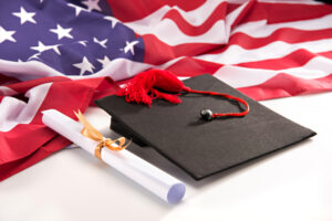 Graduation cap and diploma next to an American flag