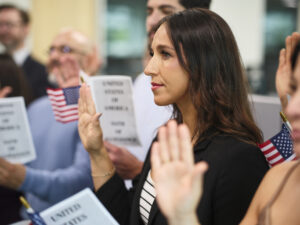 People taking the Oath of Allegiance to the United States, holding American Flags and raising their right hands